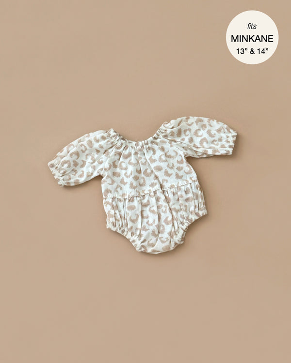 The Cotton Bertille Romper - Feline by Minikane features a tan and white leopard print design with long sleeves and an off-shoulder style, ideal for 13" to 14" Gordis dolls. Labeled "MINKANE," it's displayed on a beige background and is hand washable.