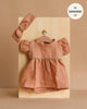 The Minikane Doll Clothing set features a rust-toned Daisy Dress with puffed sleeves and a matching headband in washed linen (Hazelnut). Fits 13-inch Minikane dolls—perfect for refreshing your doll’s wardrobe!.