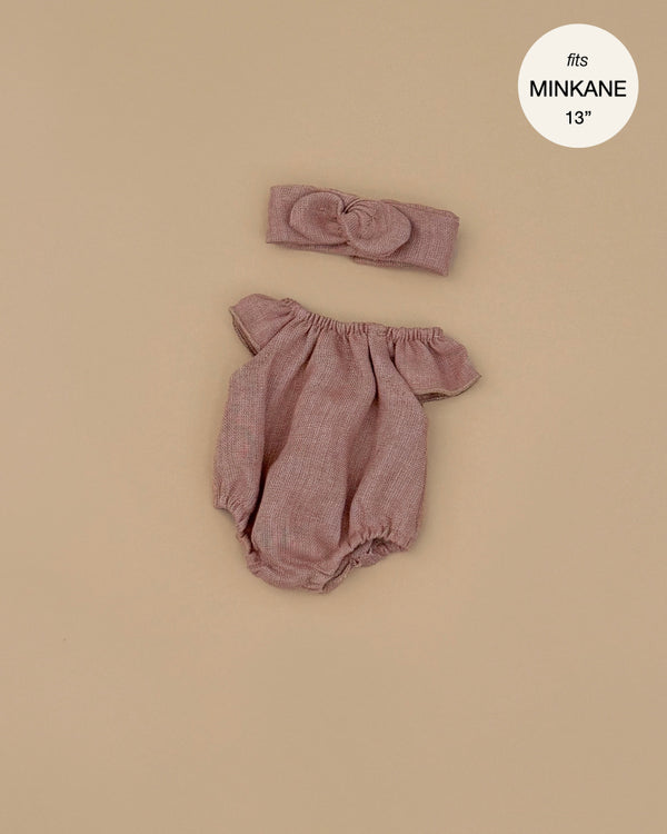 The Clara Romper & Headband in hazelnut washed linen for Minikane dolls features ruffled sleeves and comes displayed on a beige background, with a label stating it fits Minikane Gordis dolls.