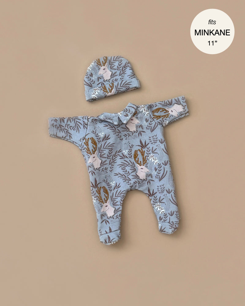 A soft blue cotton-knit baby outfit with a woodland animal pattern, featuring deer and trees, rests on a neutral background. The set includes a matching hat, perfect for Minikane Dolls. Text in the corner reads "fits MINKANE 11". Product Name: Minikane 11" Doll Clothing | Corentin.