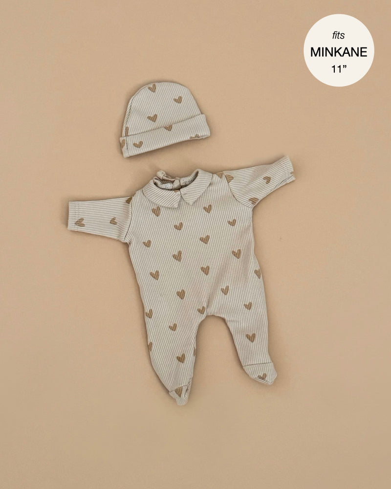 The Minikane 11" Doll Clothing | Sleep Well Corentin Onesie & Hat - Beige Hearts features a beige ribbed long-sleeve onesie and hat with brown heart patterns, made for 11-inch Minikane dolls. Displayed flat on a beige background.