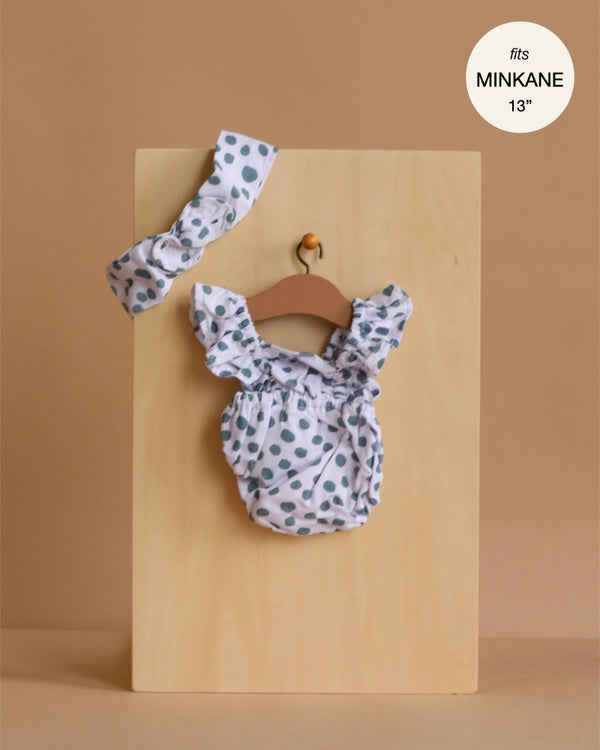 The Minikane 13" Doll Clothing | Lou Retro Romper with Headband in Cotton - Polka Dot is displayed on a wooden board with a tan background. A round label in the top right reads "fits MINIKANE 13''." Perfect for your Minikane dolls.