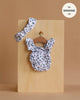 The Minikane 13" Doll Clothing | Lou Retro Romper with Headband in Cotton - Polka Dot is displayed on a wooden board with a tan background. A round label in the top right reads "fits MINIKANE 13''." Perfect for your Minikane dolls.
