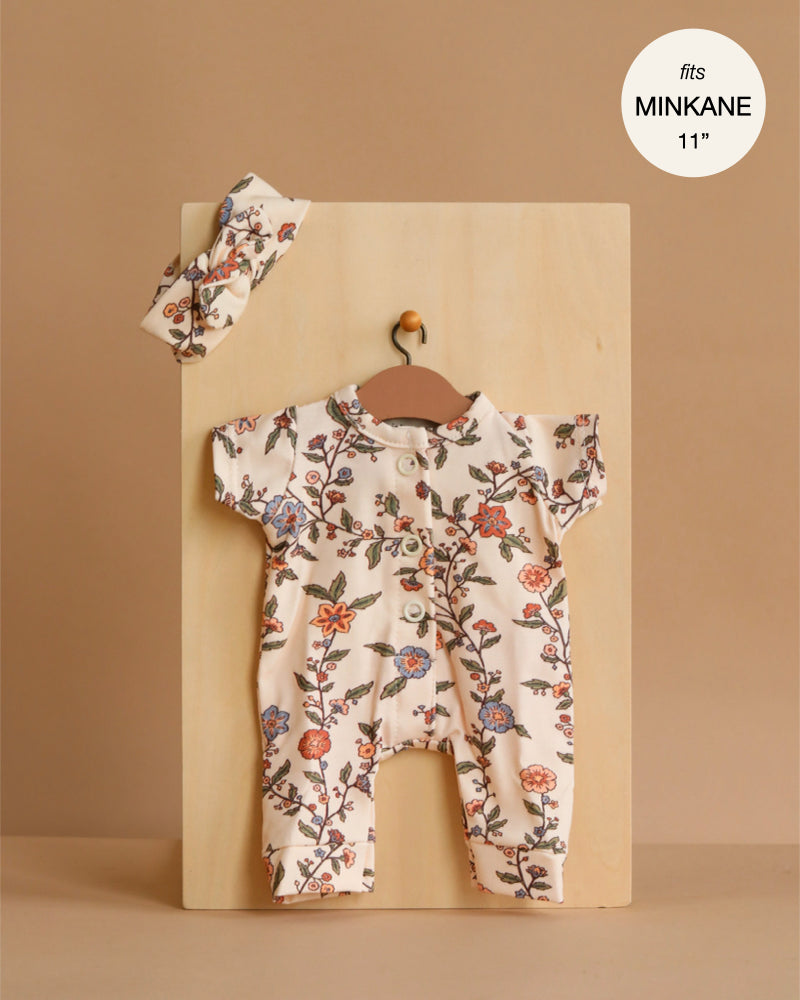 The Minikane 11" Doll Clothing | Lili Jumpsuit & Headband in Jersey - Gisele features a soft floral-print romper with short sleeves and front buttons, displayed on a mini hanger. Tag reads "fits MINIKANE 11". Made in France.