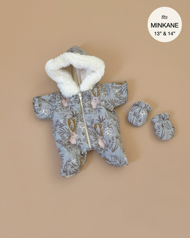 Grey snowsuit with a white faux fur hood decorated with woodland animals and leaves, paired with matching mittens. Displayed on beige, designed for Minikane dolls, the label reads "fits Minikane 13'' & 14''." Product: Minikane 11" Doll Clothing | Elaphe Pilot and Mitten Jumpsuit Set.