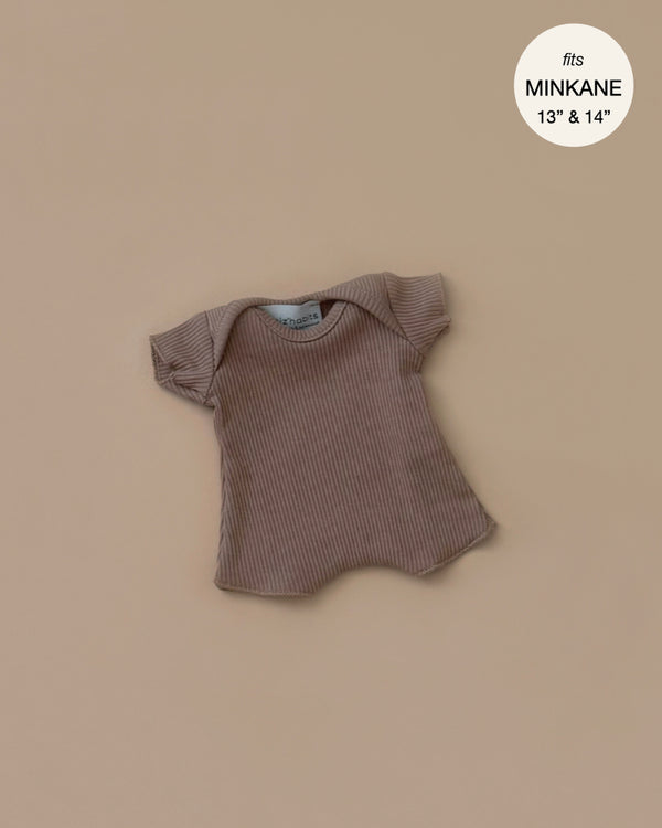 The Minikane 11" Doll Clothing, Cocoa Ribbed Body Shorty—a charming, French-made brown T-shirt crafted from cotton knit—fits 13" and 14" Minikane dolls perfectly and is displayed on a beige background.