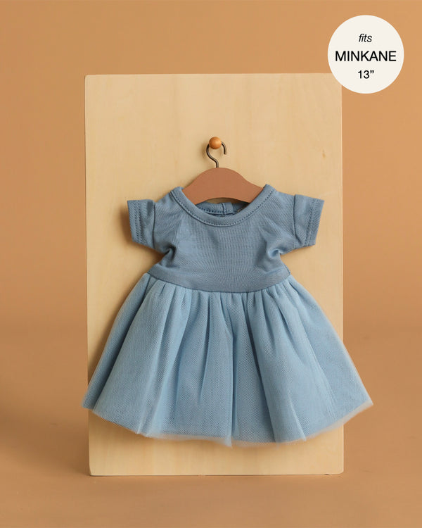 The Minikane Doll Clothing Rosana Short Sleeve Tutu in cobalt blue, featuring a knit bodice and tulle skirt, is shown on a wooden hanger. Fits 13" Minikane dolls or similar 14" dolls.