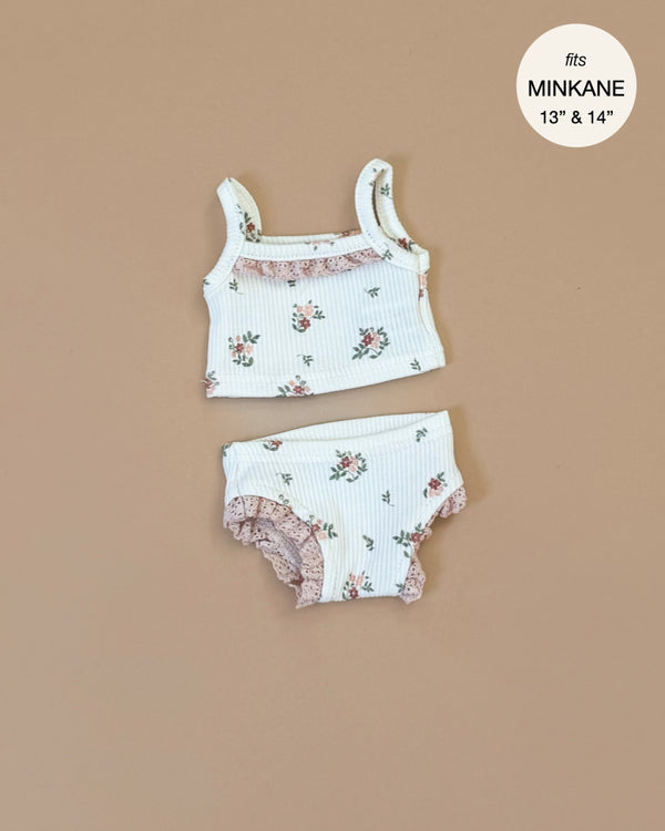 The Minikane Doll Clothing from Les P'tits Basiques features a floral-patterned tank top and matching bloomers for 13" and 14" dolls. Made in France, this white outfit with pink floral prints and lace accents on a beige background is easily hand washable for convenience.