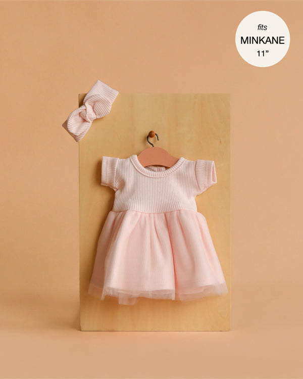 Minikane 11" Doll Clothing | Rosana Short-Sleeved Tutu and Headband in Petal Pink features a ribbed top, tulle skirt, and matching headband. Displayed on a small hanger against wood. Perfect fit for Minikane Dolls. Made in France. Fits MINKANE 11''.