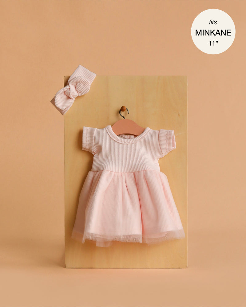 Minikane 11" Doll Clothing | Rosana Short-Sleeved Tutu and Headband in Petal Pink features a ribbed top, tulle skirt, and matching headband. Displayed on a small hanger against wood. Perfect fit for Minikane Dolls. Made in France. Fits MINKANE 11''.