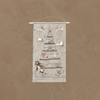 The Coral & Tusk Embroidered Advent Calendar hangs from a wooden rod and string on a plain brown textured wall, featuring a Christmas tree outlined and decorated with embroidered animals, stars, and ornaments.