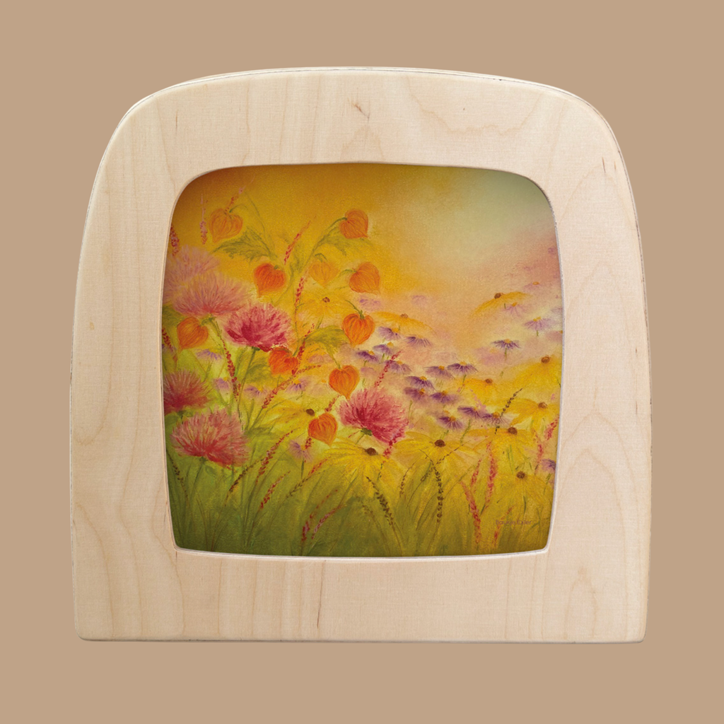 A vibrant meadow scene with pink and orange flowers and a warm yellow-orange sky is featured on the Amber Fields Silhouette, designed for the Toverlux Lamp.
