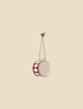 This delightful Maileg Christmas Metal Ornament - Large Red Drum showcases intricate hand-painted details in a red and white diamond pattern. It is suspended gracefully from a red and white braided string against a simple beige backdrop.