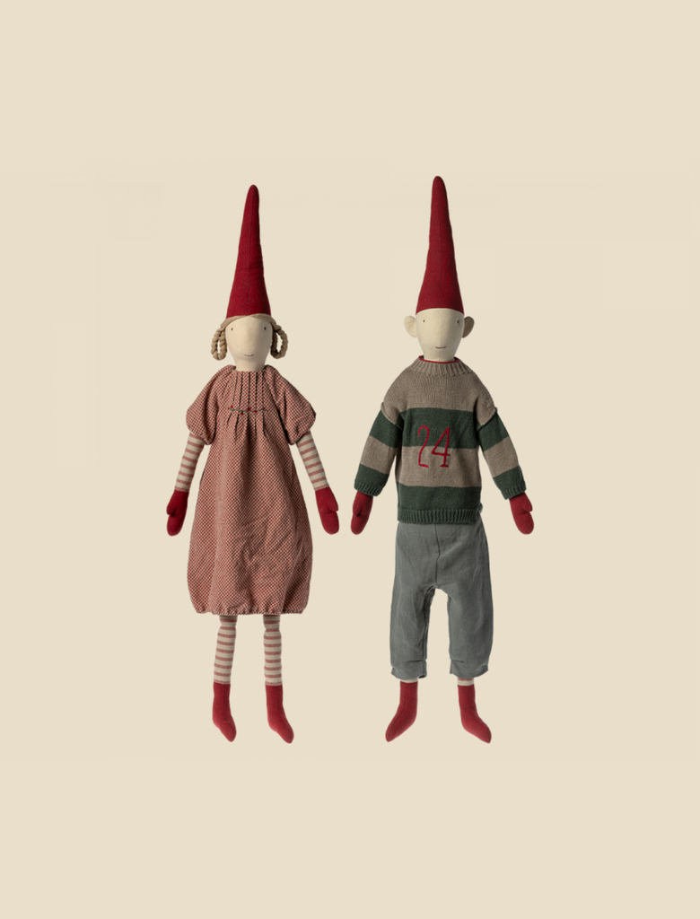 Sentence with product name: Two Maileg Christmas Pixy (Size 6) dolls dressed in exclusive materials. The doll on the left wears a striped dress and on the right, a gnome sports a sweater with the number 24 and trousers. Both have tall