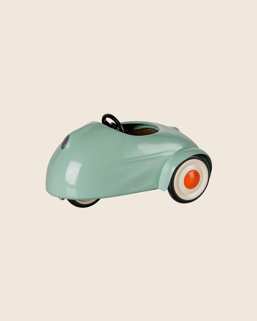 The PRE-ORDER: Maileg Car, Mouse - Light Mint (Estimated Arrival Mid August) is a small, mint green pull-along car featuring a rounded design, whitewall tires, orange hubcaps, and a black steering wheel on a beige background.