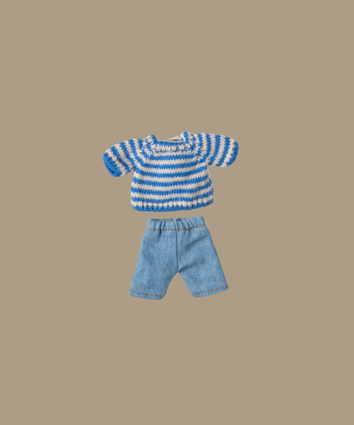 The Maileg Knitted Sweater, featuring blue and white stripes, is matched with denim shorts on a plain beige backdrop.