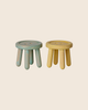 The PRE-ORDER: Maileg Stool Set, Mouse - Mint/Light Yellow (Estimated Arrival Mid July) features two small, round wooden stools in mint and light yellow with thick legs, shown on a plain light beige background.