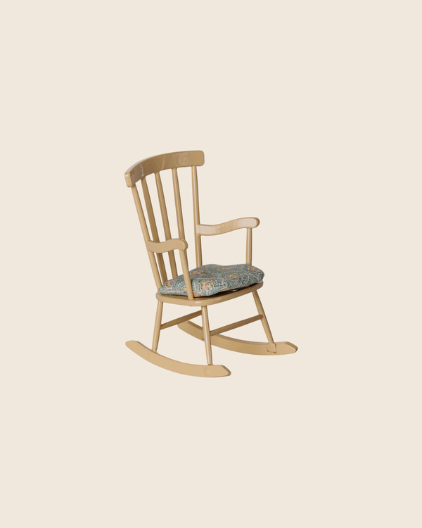 The PRE-ORDER: Rocking Chair, Mouse - Wheat (Estimated Arrival Mid August) features a light wooden frame, curved backrest and arms, and a patterned cushion—perfect for cozy moments at Mouse hole Farmhouse against a beige background.