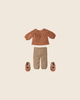 A flat lay of the PRE-ORDER: Maileg Pants and Knitted Sweater, Size 3 (Estimated Arrival Early November), with a decorative patterned brown sweater, flower-printed pants, and light brown shoes on a beige background.
