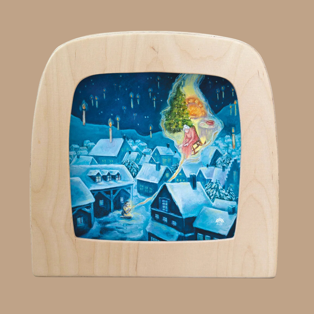 A wooden frame displays “Silhouette Only - The Little Match Girl Silhouette for Toverlux Lamp,” featuring a winter village scene at night with snow-covered houses, styled as silhouette artwork. A magical figure in pink floats above, holding a glowing tree, while candles appear in the sky, enhancing the enchanting ambiance characteristic of Magic Silhouettes.