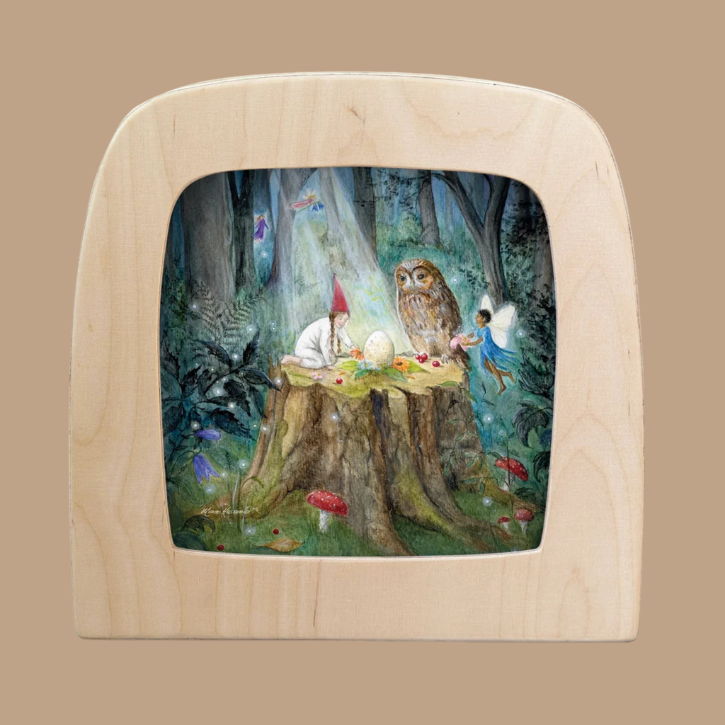 A gnome, fairy, and owl gather around a glowing egg on a tree stump in a magical forest, framed by a light wood arch on a tan background—a captivating scene depicted in the “Silhouette Only - Midsummer Ritual Silhouette for Toverlux Lamp,” an enchanting addition to your Toverlux lamp collection.