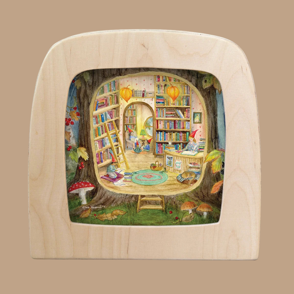 Transform your space with “The Secret Library Silhouette”—a cozy, whimsical library scene inside a tree featuring bookshelves, a ladder, two gnomes reading, colorful rugs, lanterns, and mushrooms—all framed by a light wood border. Designed exclusively for the Toverlux Lamp as part of the enchanting Toverlux Magic Silhouettes collection, this silhouette brings storybook wonder and truly unique home decor to any room.