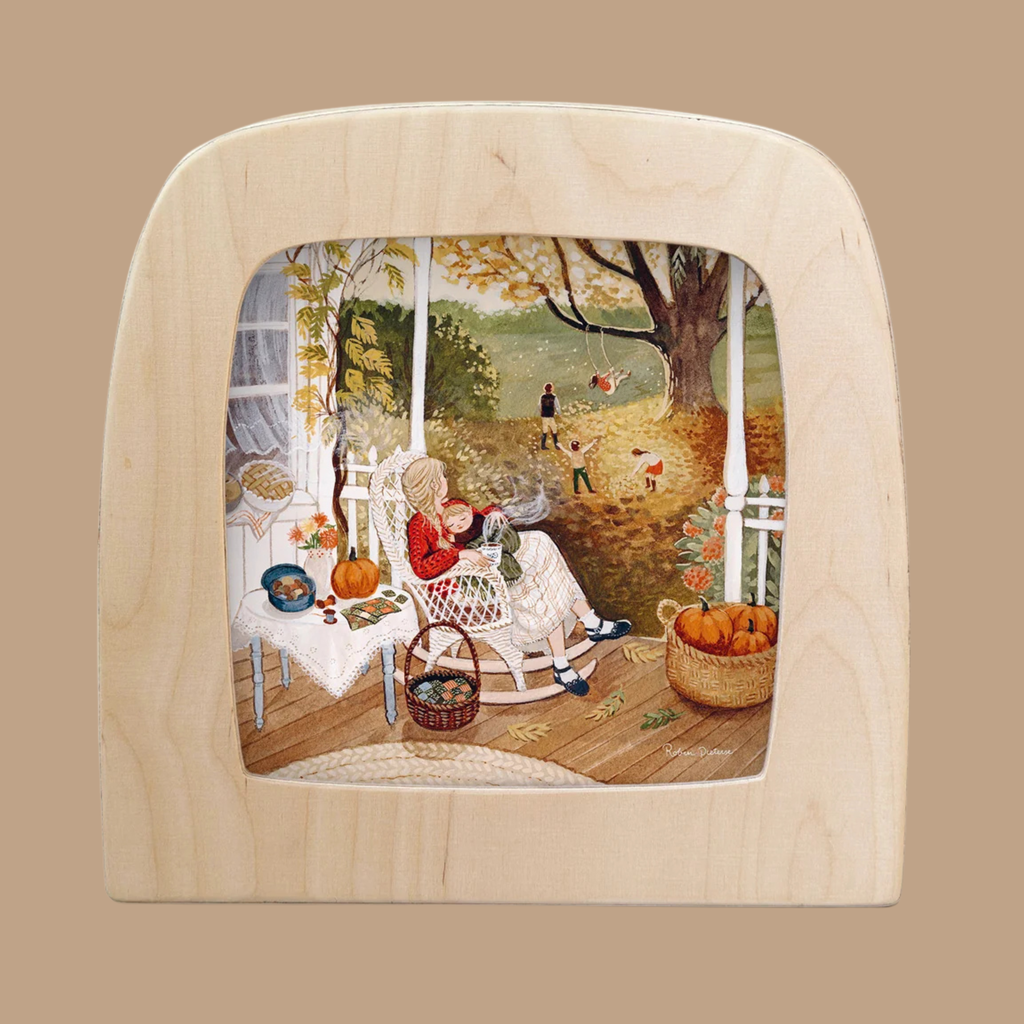 A woman reads on a porch adorned with autumn decor while children play on swings and rake leaves beneath a large tree—all beautifully captured in the “Pumpkin Spice Silhouette” designed for the Toverlux Lamp. The scene, viewed through a wooden, window-shaped frame, is brought to life with this unique Silhouette Only design for truly distinctive home decor.