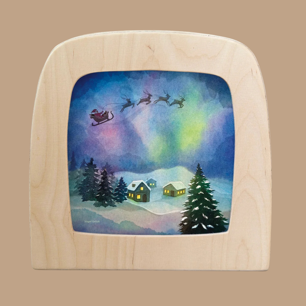 Bring a festive glow to your space with the “Silhouette Only - Aurora Sleighride Silhouette for Toverlux Lamp.” This enchanting translucent artwork features Santa’s sleigh and reindeer soaring above snowy homes and pine trees beneath a vibrant aurora borealis night sky. Reminiscent of Magic Silhouettes, this decorative piece casts a magical, heartwarming light when displayed with your Toverlux Lamp.