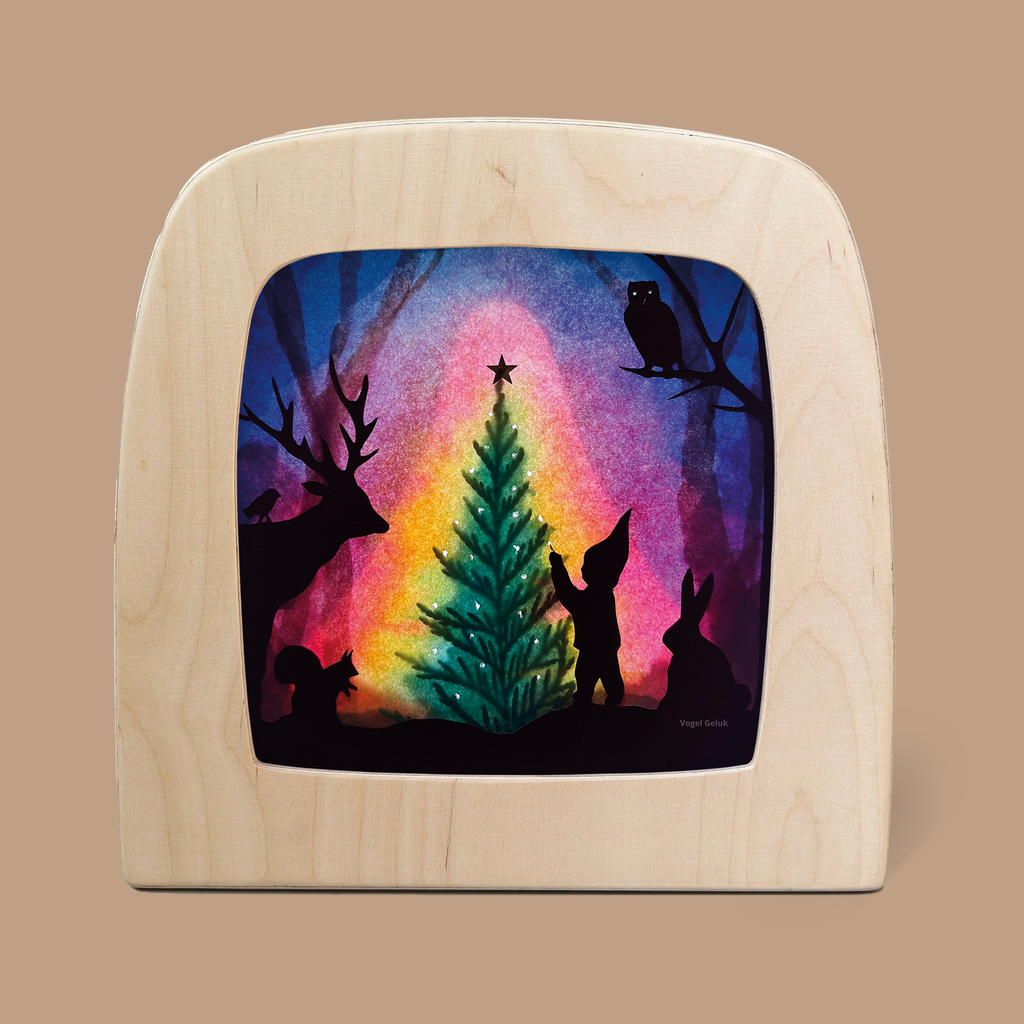 A captivating Christmas tree silhouette with a deer, squirrel, rabbit, gnome, and owl crafted from translucent material illuminates against a vibrant background. This enchanting scene is beautifully framed within a wooden arch and perfectly complements the Toverlux Lamp.