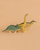 The Handmade Holzwald Dinosaur Set features a green Triceratops, yellow Brachiosaurus, and beige Tyrannosaurus rex standing together on a plain beige background, highlighting their handcrafted charm.