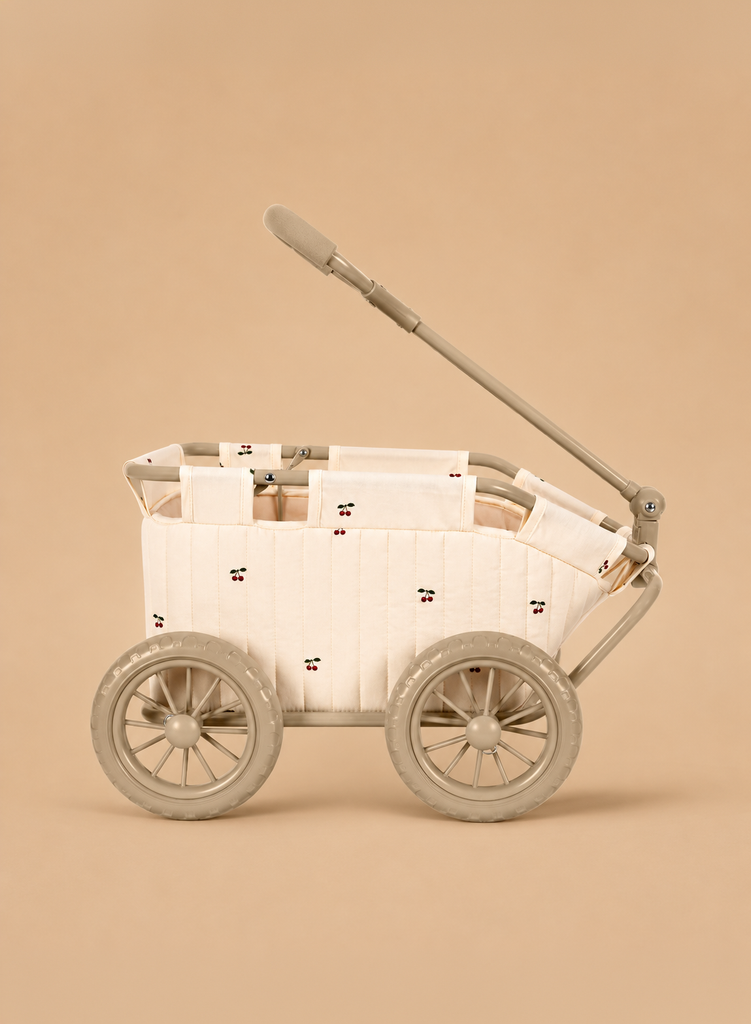 The Konges Sloejd Stoller Kids Wagon - Cherry features a beige quilted fabric cover adorned with small cherry embroidery and four large plastic wheels, displayed against a matching beige background.