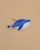 The Minke Whale Pencil Case, in blue and white and handcrafted in Spain from 100% cotton, rests on a beige surface with a pencil partly tucked into its zipper opening.