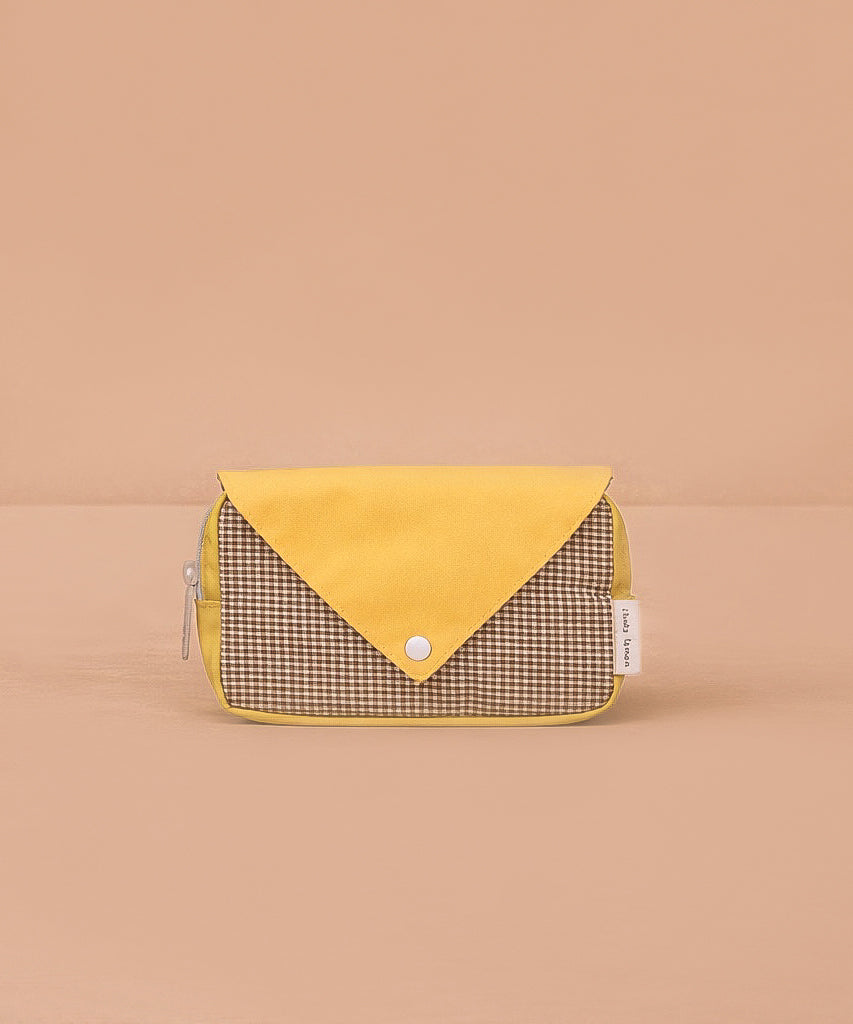 The Sticky Lemon Fanny Pack Small - Envelope - Apple Juice features a yellow flap, snap button closure, and brown checkered front made from recycled PET bottles, shown on a plain light brown background.
