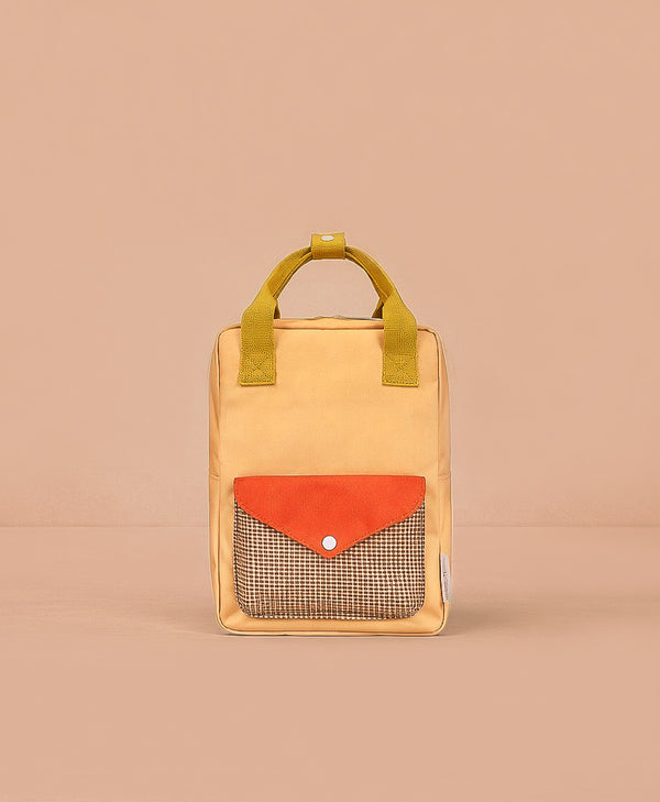 The Sticky Lemon Backpack Small - Envelope - Apple Juice is a small, rectangular yellow backpack with short handles, an orange front pocket flap, checkered pattern beneath the flap, made from recycled PET bags and shown on a plain beige background.