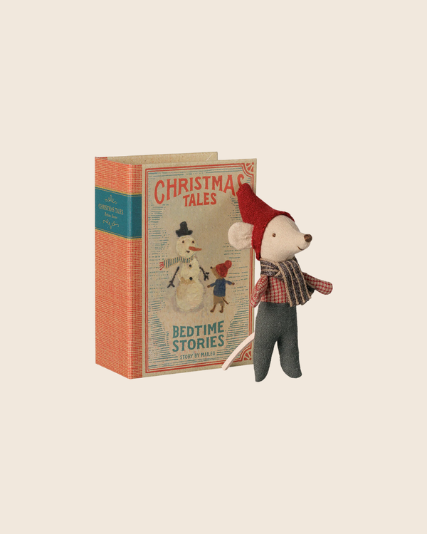 The PRE-ORDER: Maileg Christmas Mouse, Baby in Book features a baby mouse in a red hat and scarf standing beside the "Christmas Tales Bedtime Stories" book with a snowman and child on the cover. Estimated arrival: early September.