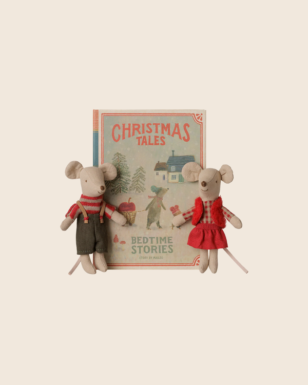 The PRE-ORDER: Maileg Christmas Twin Mice, Little Sister and Brother in Book features two cotton-filled mice dolls—one in red overalls and one in a red dress—sitting before a vintage-style “Christmas Tales Bedtime Stories” book.
