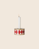 A white candle glows in the PRE-ORDER: Maileg Christmas Candle Holder, Drum - Red/Off White, featuring red diamonds on a cream background with gold trim—perfect for cosy Christmas decor. Estimated arrival mid October.