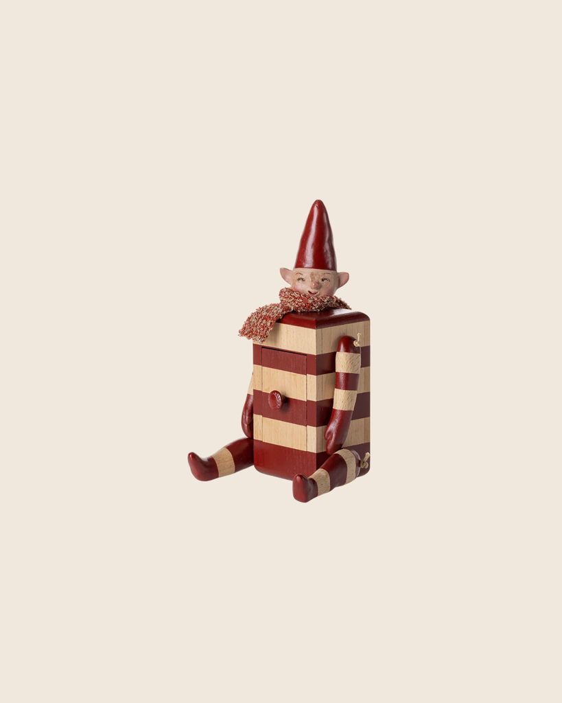The PRE-ORDER: Maileg Elf with Drawer - Red (Estimated Arrival Mid August) features a whimsical elf figurine with a red hat and scarf, sitting with outstretched legs on a striped box-shaped body that includes a small drawer. Set against a light beige background.