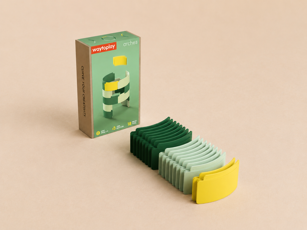 A box labeled “WaytoPlay: Arches - Starter Set” stands next to a stack of plastic curved arches in yellow, dark green, and light green, all arranged neatly on a beige surface—perfect for imaginative play with this creative building set.