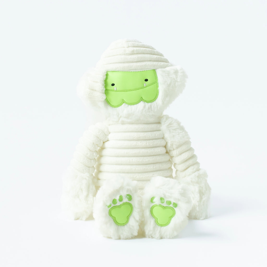 A glow-in-the-dark Slumberkins Halloween Gift Set - Mummy Kin plush toy, with white fabric wrappings and lime green accents on the feet and face, sitting against a white background.