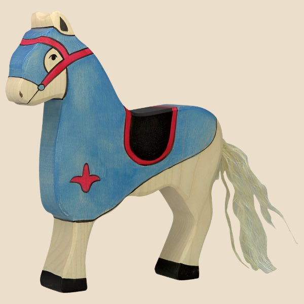 The Holztiger Tournament Horse, Blue is a handcrafted wooden toy horse made in Europe, painted light blue with red and black accents, cream mane and tail, and black hooves. Ships in one week.