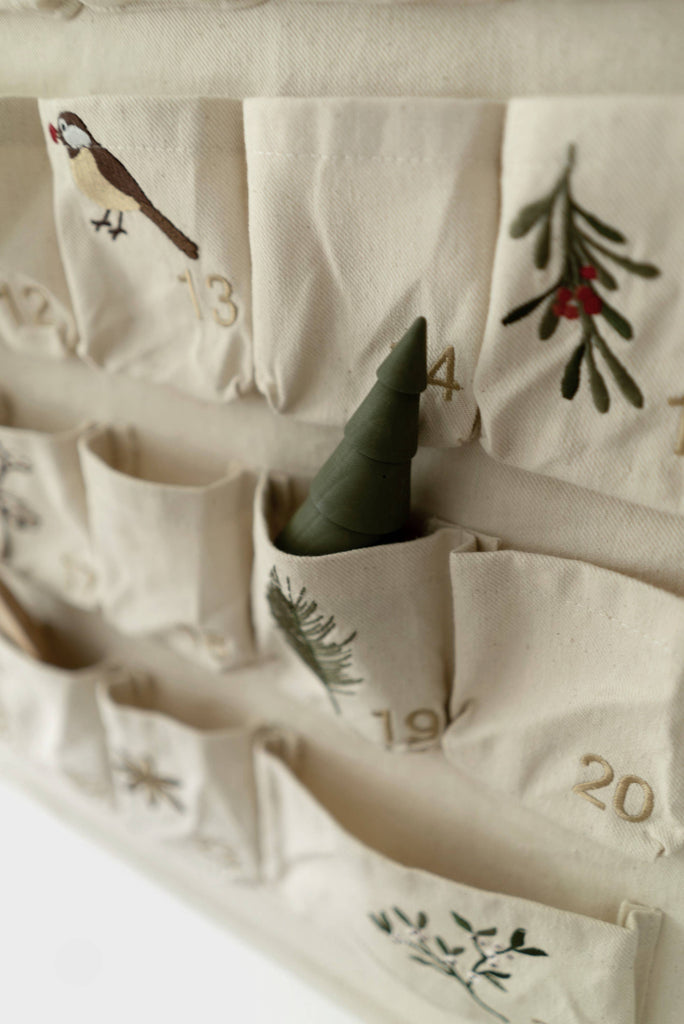The Sabo Concept Christmas Cotton Advent Calendar features numbered pockets with festive bird and greenery embroidery, plus a small green tree-shaped object in pocket 14.