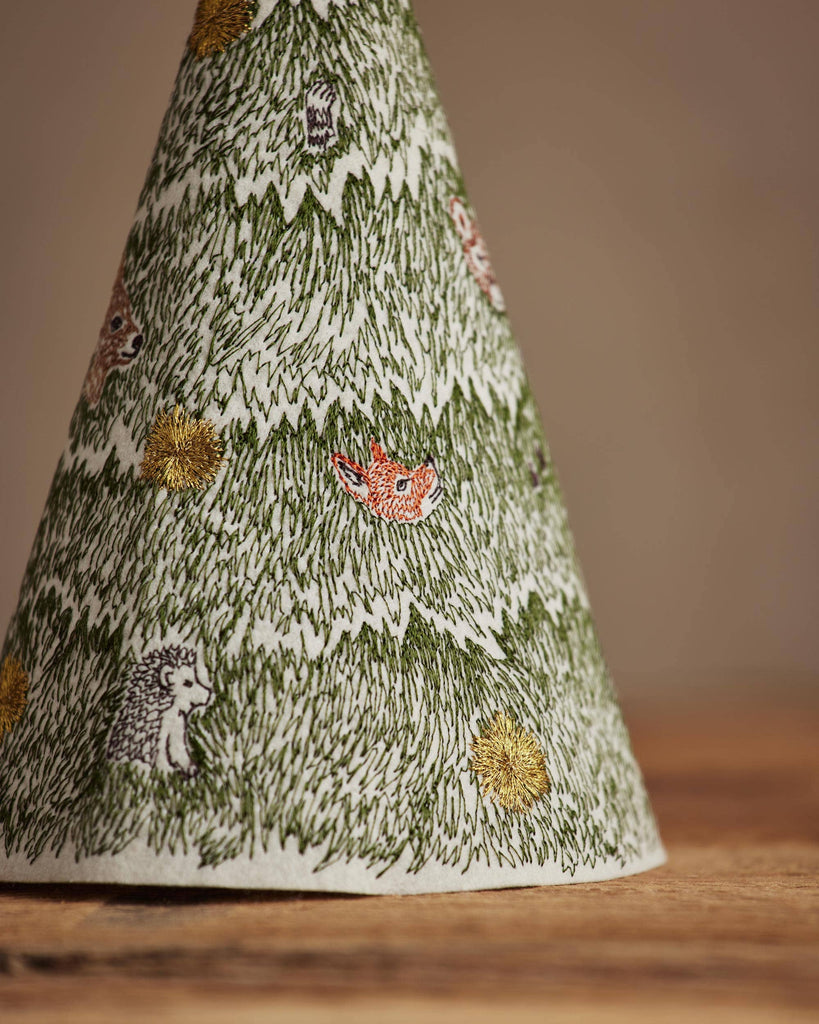 Coral & Tusk Peek a Tree Tree is a cone-shaped felt ornament featuring embroidered green pine needles, gold stars, and small woodland creatures including a fox and hedgehog.