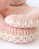 Close-up of two soft Cuddle + Kind Baby Octopus toys in soft coral pink, hand-knit from heirloom-quality Peruvian cotton yarn, highlighting their textured stitches and cozy feel.