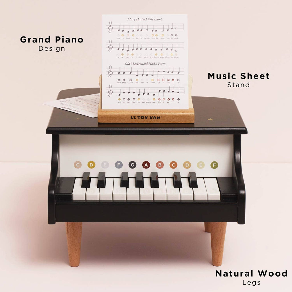 The Wooden Grand Piano Toy is a small black piano with labeled keys, a music sheet stand holding sheet music, and natural FSC-certified wood legs. Features include "Grand Piano Design," "Music Sheet Stand," and "Natural Wood Legs.