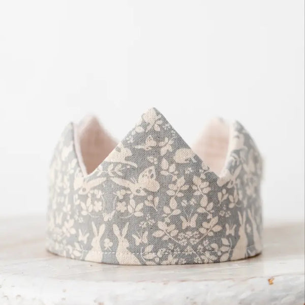 A Forest Reversible Birthday Crown with a delicate floral and rabbit print, displayed against a light background, embodying a minimalist and whimsical design. This reversible crown is crafted from organic cotton.