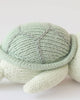 A close-up of the Cuddle + Kind Baby Sea Turtle (Kelp Green), showcasing its hand-knit textured shell and soft flippers against a plain white background—an adorable, heirloom-quality toy.