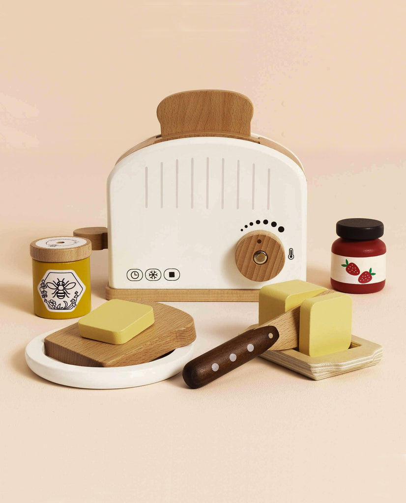 The Pop-up Toaster & Breakfast Set (ships in one week) includes a white toaster, bread slices, butter, knife, honey jar with bee label, and strawberry jam—all made from FSC-certified wood on a light beige background.