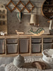 A cozy children’s room with wooden storage bins, a whale-shaped night light, toy vehicles, a Hot Air Balloon - Light Brown / Green decoration, and soft neutral-toned decor including a basket and quilted mat.