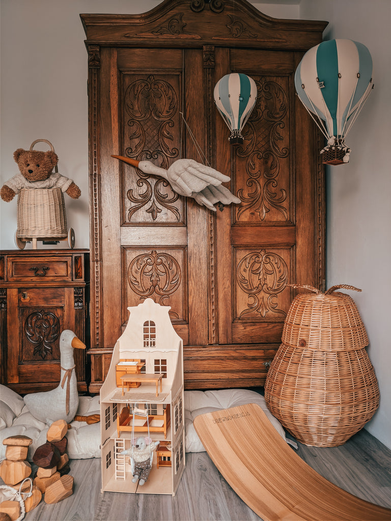 A cozy children's room with a vintage wooden wardrobe, wicker baskets, a teddy bear, handmade decor, plush toys, a toy goose, a dollhouse, and the Hot Air Balloon - Mint Green and Grey featured as charming wall decor above the wooden floor.